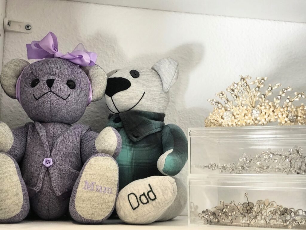 Two memory bears labeled "Mum" and "Dad" displayed beside decorative tiaras, representing meaningful items saved during the decluttering process.